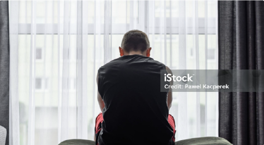 man sat on bed with his back to the camera