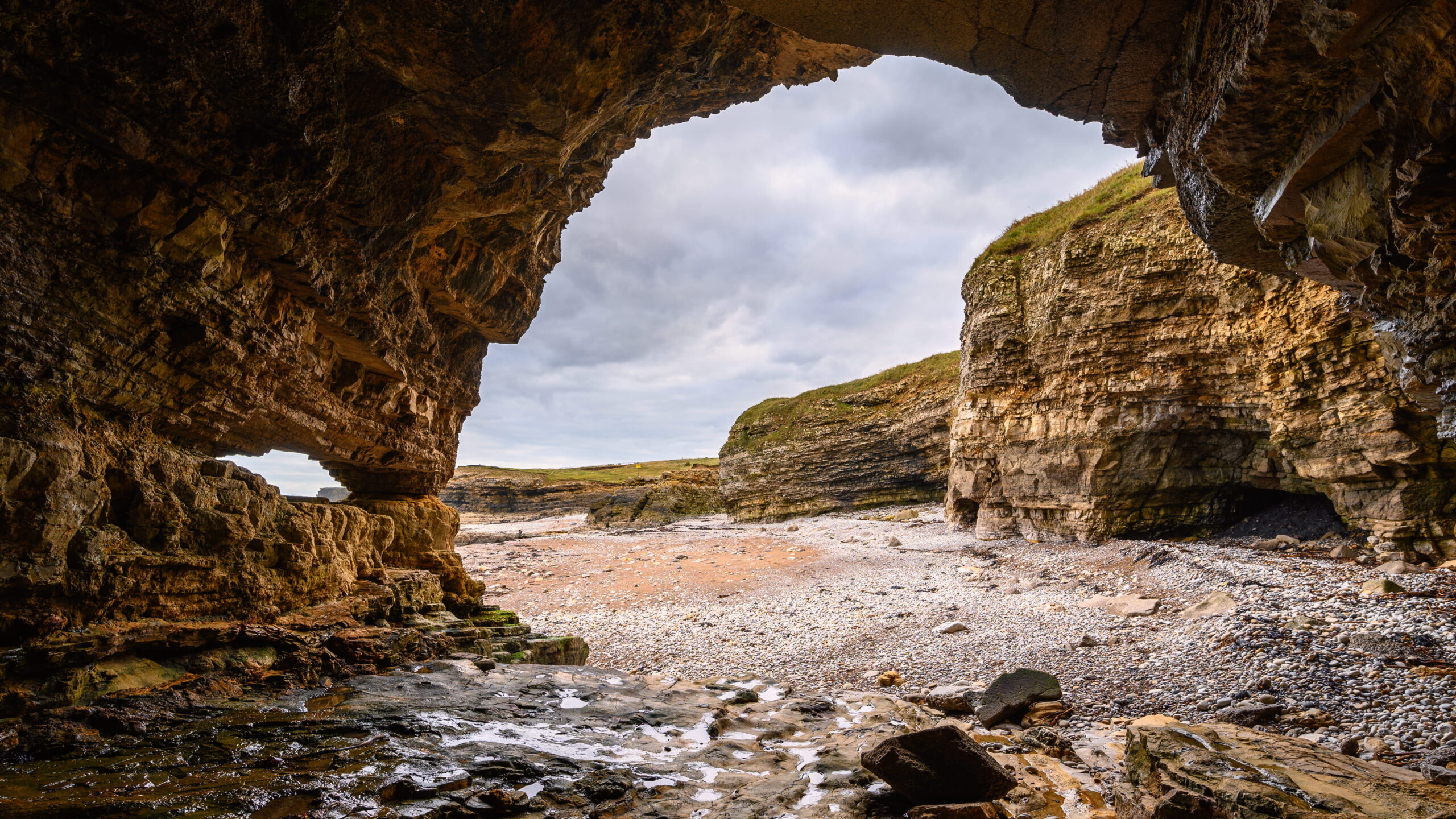 looking through rock face towards cliffs at the beach