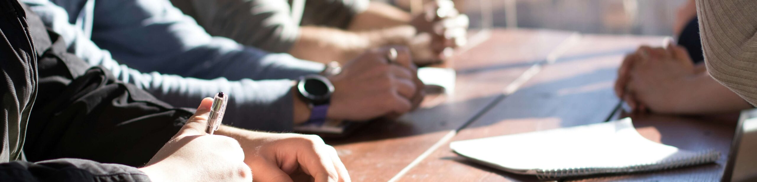 paper and pens and hands on a table