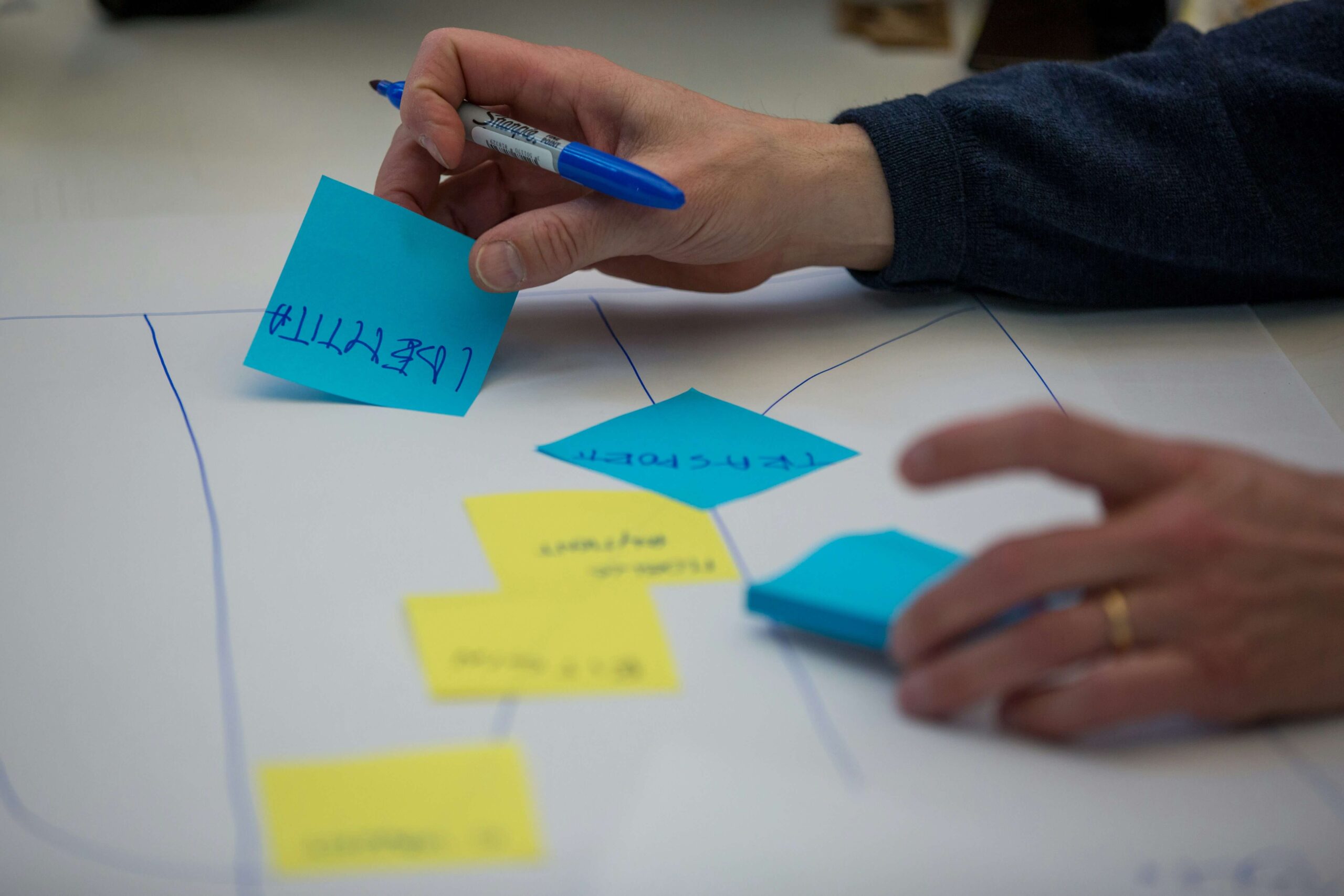 postit's with writing on and hand holding a blue pen