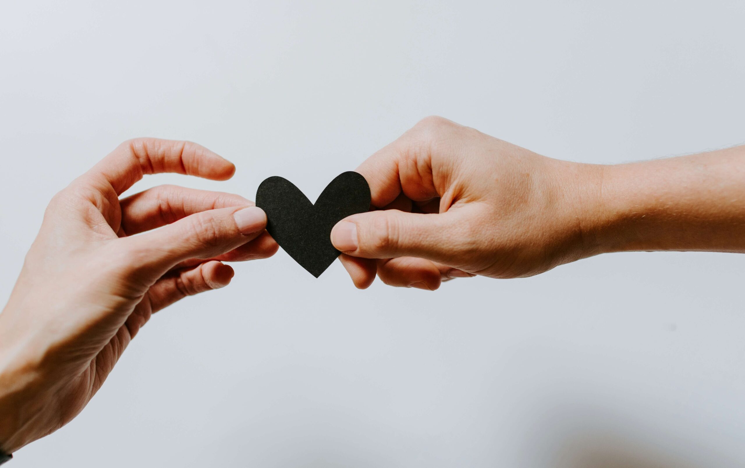 two people holding black papercut heart