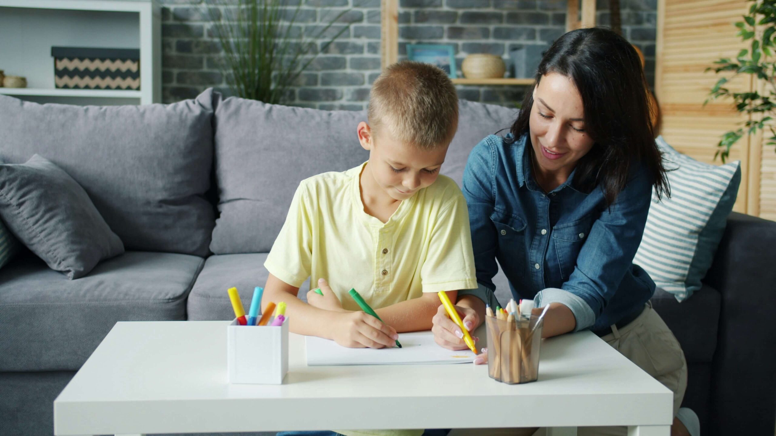Adult and child sitting on a sofa at a low table colouring